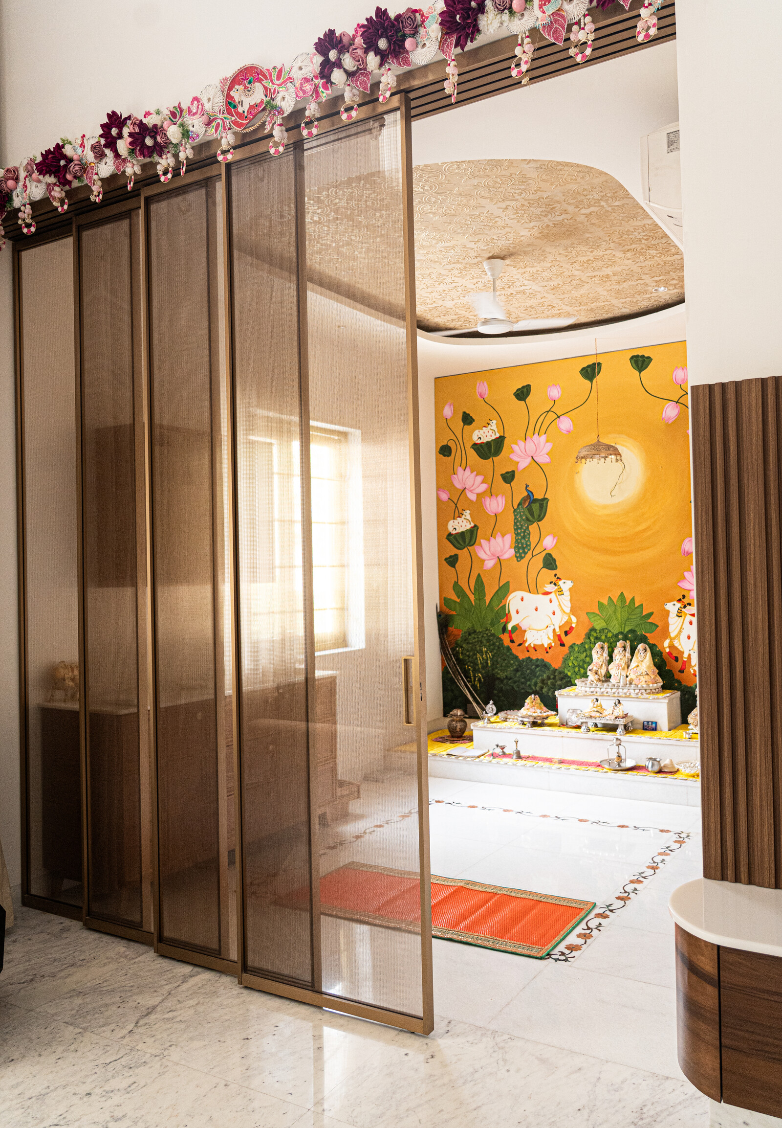 Bronze-framed sliding partition revealing a serene Indian puja room
